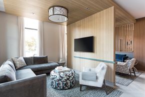 Washington apartment for rent - A modern living room with a grey couch, a black TV, and a wooden wall.