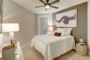 Charlotte apartment for rent - A bedroom with a white bed and a ceiling fan.
