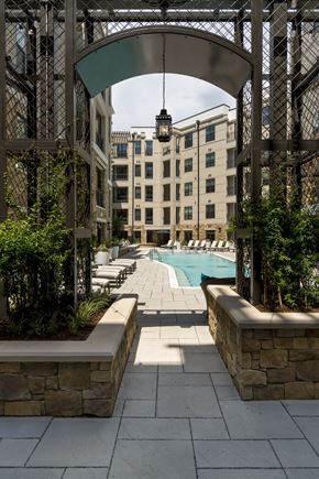 Charlotte apartment for rent - A pool area with a metal trellis and a stone wall.
