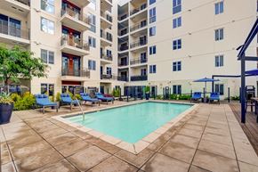Los Angeles apartment for rent - A large swimming pool surrounded by a tiled patio and lounge chairs.
