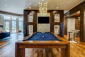 Charlotte apartment for rent - A pool table in the middle of a room with a TV and a chandelier.