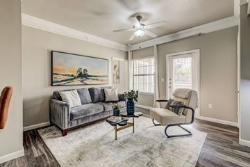 San Antonio apartment for rent - A living room with a grey couch, a chair, and a painting on the wall.