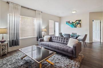 Northglenn apartment for rent - A modern living room with a grey sofa and a glass coffee table.