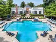 Gahanna apartment for rent - A large swimming pool surrounded by lounge chairs and a house in the background.