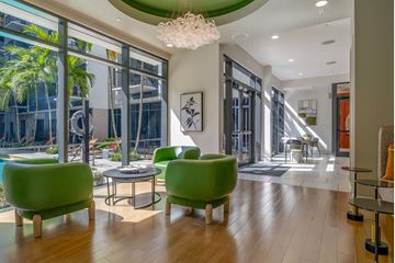 Miami apartment for rent - a living room with green chairs and a chandelier