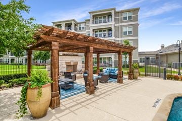 Wylie apartment for rent - A large patio area with a wooden pergola and a pool.