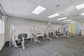San Jose apartment for rent - A gym with a variety of equipment including a weight bench, a leg press machine, and a cable machine.
