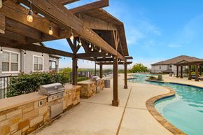 San Antonio apartment for rent - A wooden pergola over a swimming pool with a stone wall and grill.