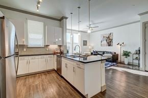 Rowlett apartment for rent - A modern kitchen with white cabinets and a wooden floor.