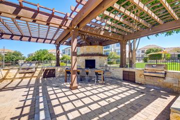 Austin apartment for rent - A patio with a table and chairs under a wooden pergola.