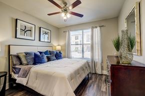 Austin apartment for rent - A bedroom with a bed, a dresser, and a ceiling fan.