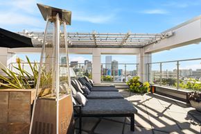 San Francisco apartment for rent - A rooftop patio with a couch, plants, and a city view.