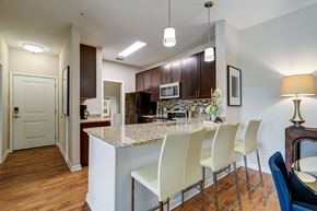 Orlando apartment for rent - A kitchen with a marble island and white chairs.