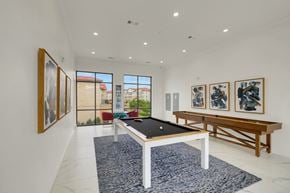 Grand Prairie apartment for rent - A pool table is in the middle of a room with a blue rug and pictures on the wall.