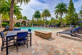 Lutz apartment for rent - A pool area with a table and chairs and palm trees.