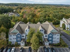 Westborough apartment for rent - A large building with a green roof is surrounded by trees and cars.