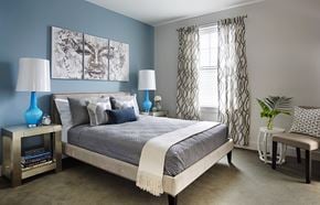Charlestown apartment for rent - A bedroom with a bed, two lamps, a painting, and a plant.