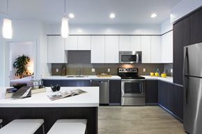 San Jose apartment for rent - A modern kitchen with a stainless steel refrigerator, a microwave above the stove, and a dining table with chairs.