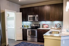 Dallas apartment for rent - A kitchen with brown cabinets and a white refrigerator.