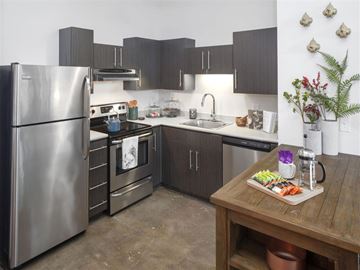 Portland apartment for rent - A modern kitchen with a wooden table holding a tray of food and a vase of flowers.