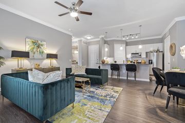 Rowlett apartment for rent - A living room with a blue couch and a ceiling fan.