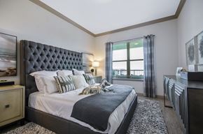 Rowlett apartment for rent - A bedroom with a large bed and a window with a view.