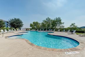 San Antonio apartment for rent - A large outdoor swimming pool with lounge chairs and a clear blue sky.