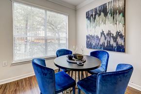 Houston apartment for rent - A dining room with a round table and blue chairs.