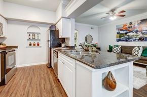 Houston apartment for rent - A kitchen with a dark refrigerator and a wooden floor.