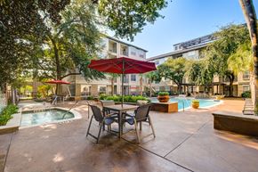 Houston apartment for rent - A patio with a table and chairs and a pool.