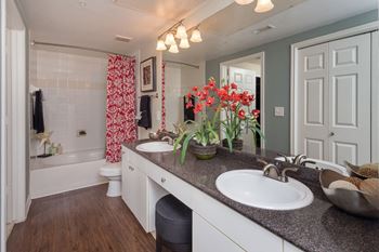 Master bathroom with floating vanities, quartz countertops, backlit vanity mirror, walk-in shower with euro shower door and quartz-topped bench seat