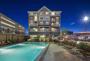 Hackensack apartment for rent - A large building with a pool in front of it.