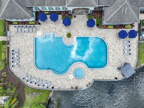 Orlando apartment for rent - An aerial view of a swimming pool surrounded by blue umbrellas and lounge chairs.