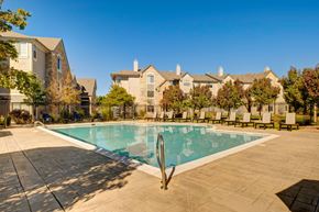 Westminster apartment for rent - A swimming pool surrounded by a tiled patio and lounge chairs in front of a row of houses.