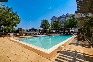 Hackensack apartment for rent - A large outdoor swimming pool surrounded by lounge chairs and trees.