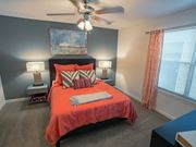 Columbus apartment for rent - A bedroom with a bed, two lamps, a ceiling fan, and a painting on the wall.