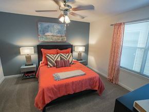 Columbus apartment for rent - A bedroom with a bed, two lamps, a ceiling fan, and a painting on the wall.