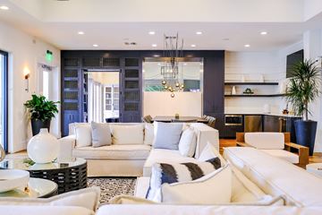 Magnolia apartment for rent - A modern living room with white furniture and a large window.