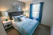 Grove City apartment for rent - A bedroom with a bed, nightstands, and a window with blue curtains.