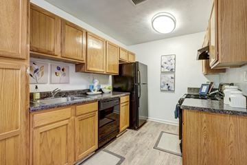Smyrna apartment for rent - A kitchen with wooden cabinets and a black refrigerator.