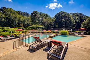 Smyrna apartment for rent - A large outdoor swimming pool surrounded by trees and lounge chairs.