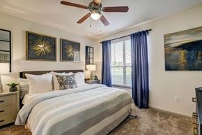 Houston apartment for rent - A bedroom with a large bed and a ceiling fan.