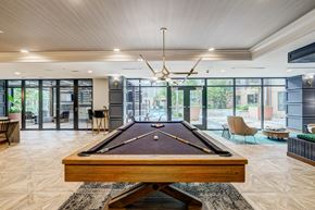 Washington Dc apartment for rent - A pool table is in the middle of a room with a wood floor and a ceiling fan.