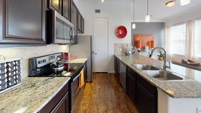 Aubrey apartment for rent - A kitchen with dark brown cabinets and granite countertops.