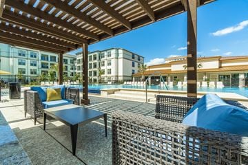 Rowlett apartment for rent - A patio with a table and chairs overlooking a pool.