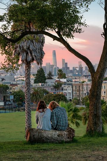San Francisco apartment for rent - Two people sitting on a tree trunk looking at the city skyline.