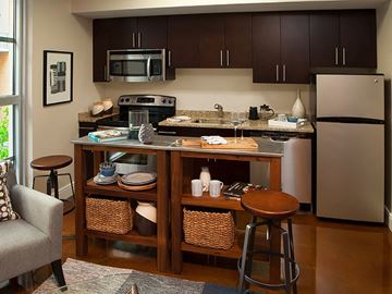 Washington apartment for rent - A kitchen with a refrigerator, microwave, oven, and a table with chairs.