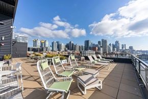 Seattle apartment for rent - A rooftop patio with several chairs and a view of a city skyline.