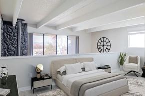 Aurora apartment for rent - A bedroom with a large bed, a chair, and a clock on the wall.