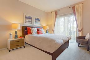 Orlando apartment for rent - A bedroom with a large bed, a nightstand with two lamps, and a chair.